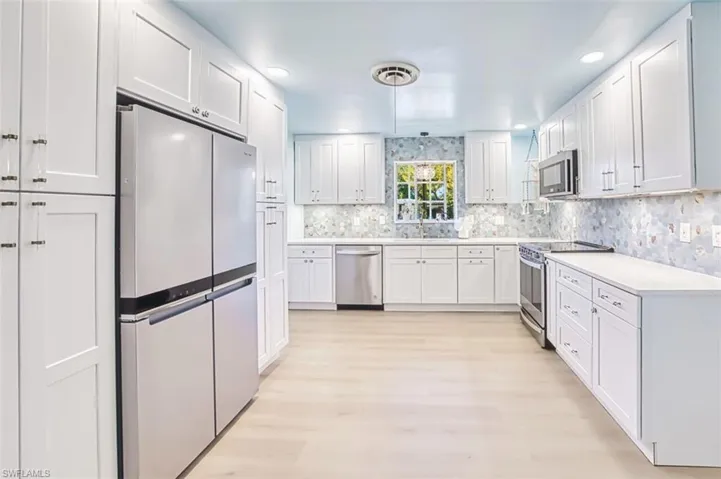 Kitchen featuring stainless steel appliances, white cabinets, light wood-style flooring, and recessed lighting