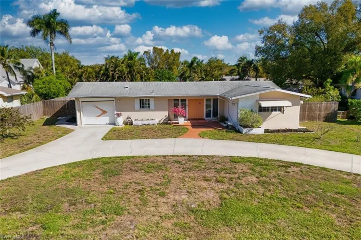 Darling Mid-century modern (MCM) home with circular driveway, an attached garage, and stucco siding.
