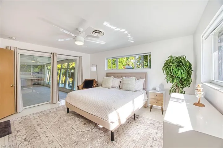 Primary Bedroom with access to exterior, multiple windows, and a ceiling fan