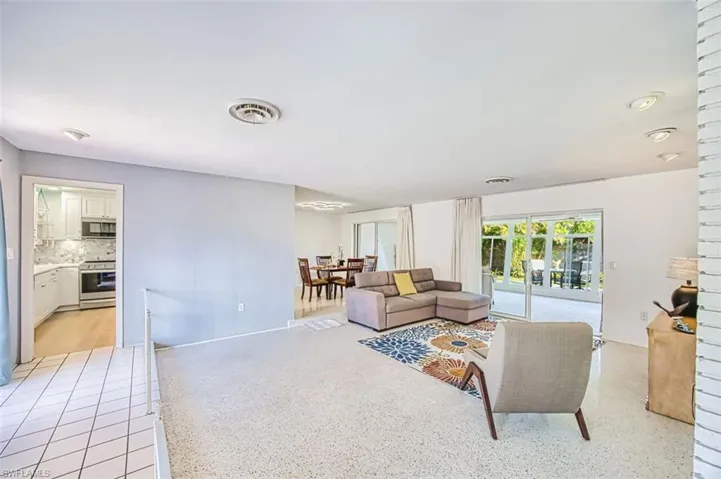 Living room featuring terrazzo tile flooring and large sliders to enclosed sunroom.