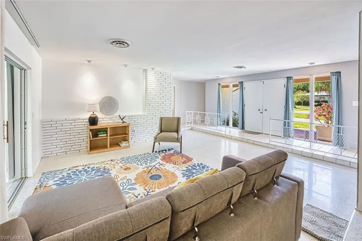 View of living room with brick wall and terrazzo tile floors.