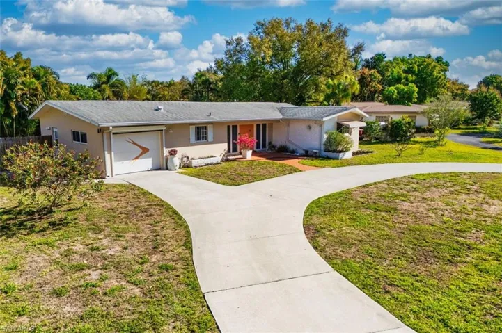 Single story home featuring concrete curcular driveway, an attached garage, and a front lawn