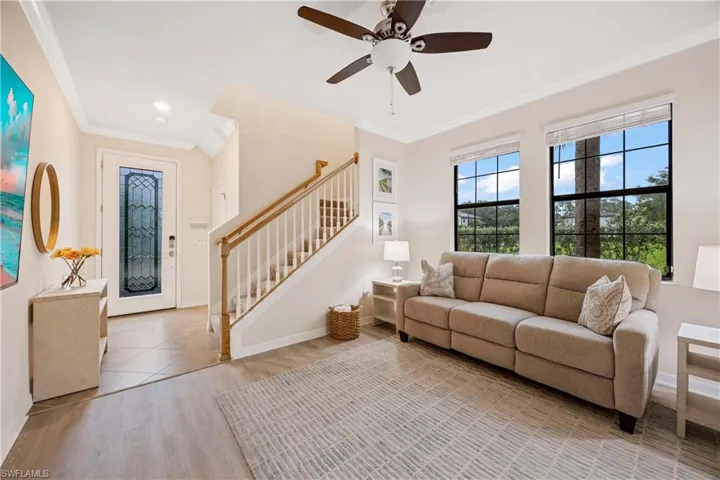 Living area with stairway, wood finished floors, crown molding, and a ceiling fan