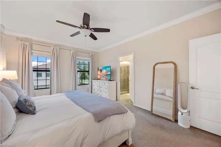 Bedroom featuring light carpet, crown molding, connected bathroom, and ceiling fan