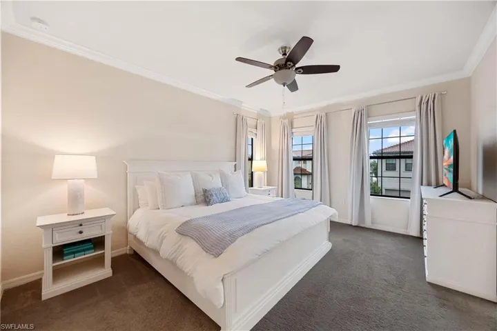 Bedroom featuring dark carpet, crown molding, and ceiling fan