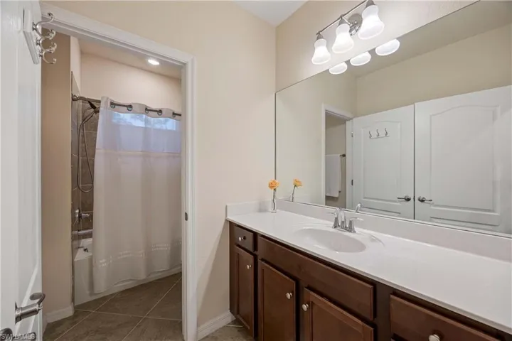 Bathroom with vanity, shower / tub combo, and tile patterned floors