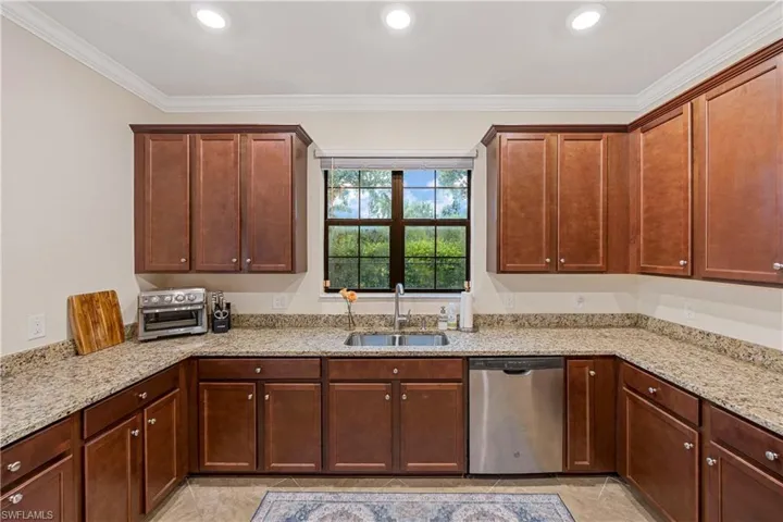 Kitchen with stainless steel dishwasher, light tile patterned flooring, light stone countertops, crown molding, and recessed lighting
