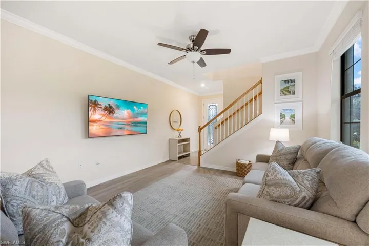 Living room featuring wood finished floors, crown molding, stairs, ceiling fan, and recessed lighting