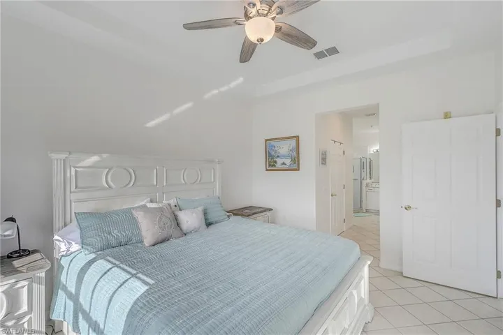 Bedroom featuring light tile patterned floors, ceiling fan, and ensuite bath
