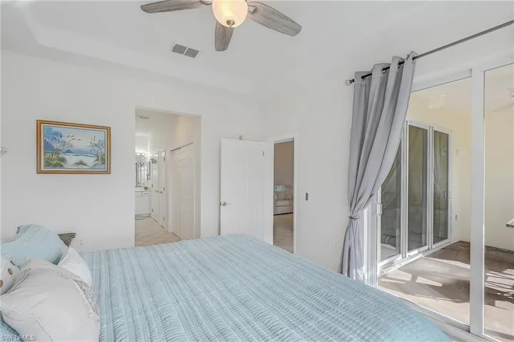 Bedroom with access to exterior, a ceiling fan, and connected bathroom
