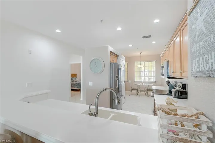 Kitchen with pendant lighting, appliances with stainless steel finishes, recessed lighting, light brown cabinets, and light stone counters