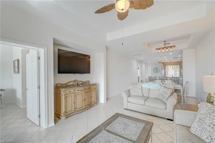 Living area featuring a raised ceiling, light tile patterned floors, a ceiling fan, and recessed lighting