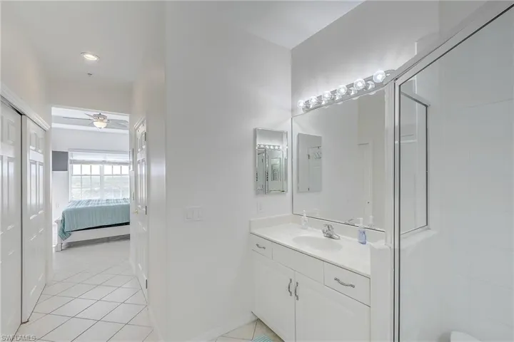 Full bathroom featuring vanity, light tile patterned floors, ensuite bathroom, a stall shower, and ceiling fan