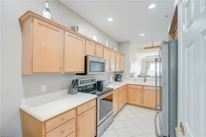 Kitchen with light brown cabinets, stainless steel appliances, light countertops, light tile patterned flooring, and recessed lighting