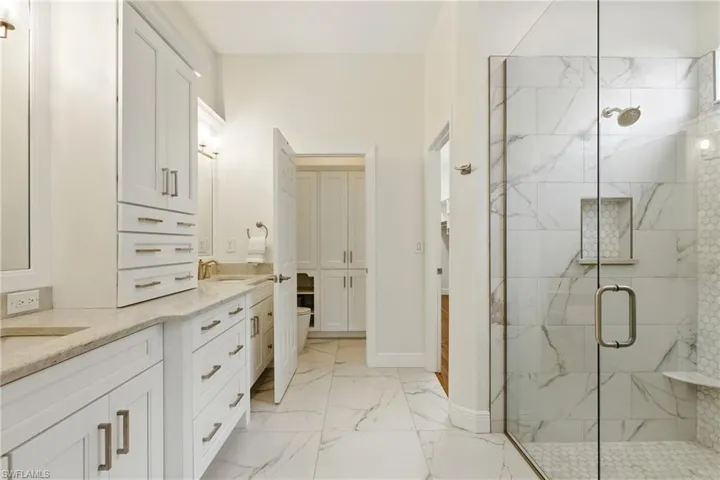 The pier cabinet separating the dual sinks has plenty of additional storage space as well as the custom cabinetry in the private water closet