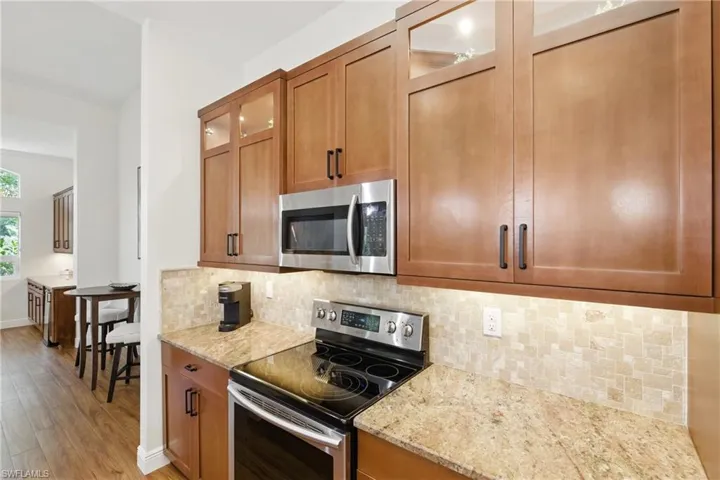 The kitchen cabinets feature decorative glass doors at the top, a neutral palette with the granite counters and backspalsh