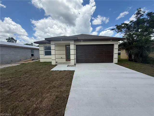 View of front facade featuring an attached garage, stucco siding, concrete driveway, and a front yard