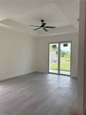 Unfurnished room with a tray ceiling, ceiling fan, wood finished floors, and crown molding