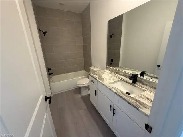 Full bath featuring vanity, wood finished floors, and washtub / shower combination