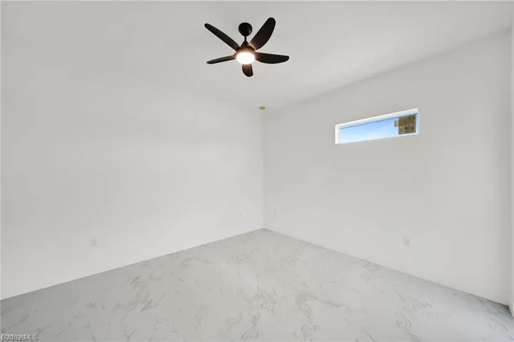 Unfurnished room with ceiling fan and marble finish floors