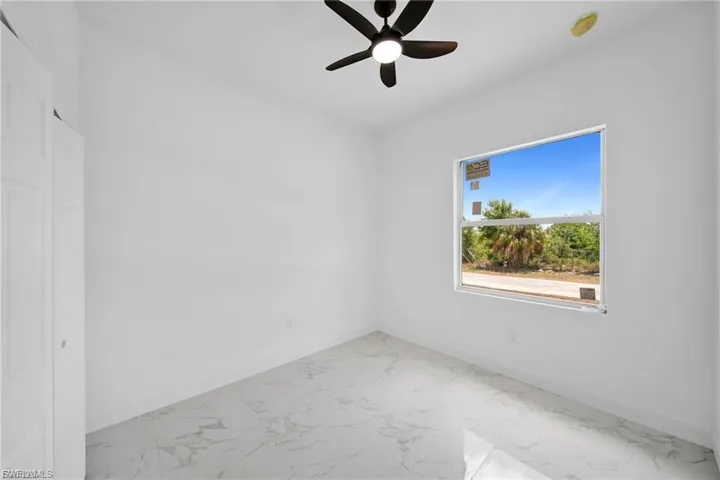 Empty room featuring light marble finish flooring and ceiling fan