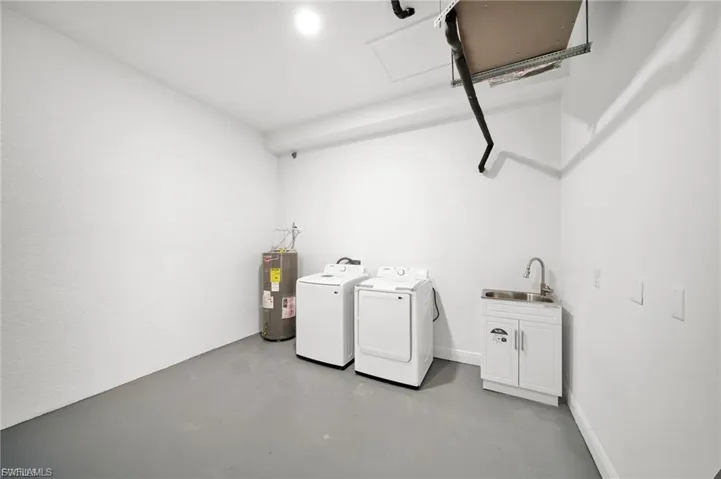 Laundry room with concrete floors, independent washer and dryer, and electric water heater