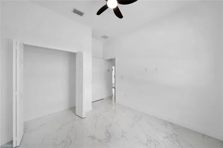 Unfurnished bedroom with light marble finish flooring, a closet, and ceiling fan