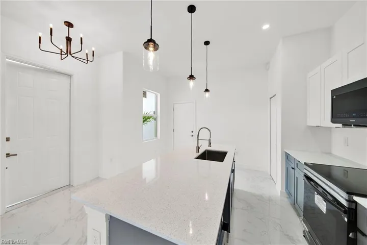 Kitchen featuring light marble finish flooring, white cabinetry, light stone countertops, and recessed lighting