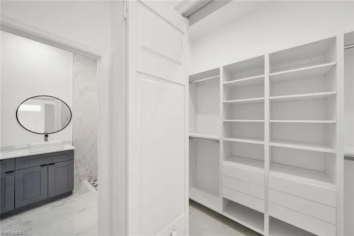 Spacious closet featuring light marble finish flooring and a sink