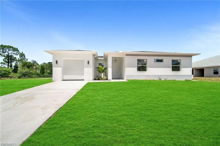 View of front of home with driveway, a front lawn, stucco siding, and a garage