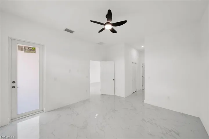 Unfurnished room featuring ceiling fan and light marble finish floors