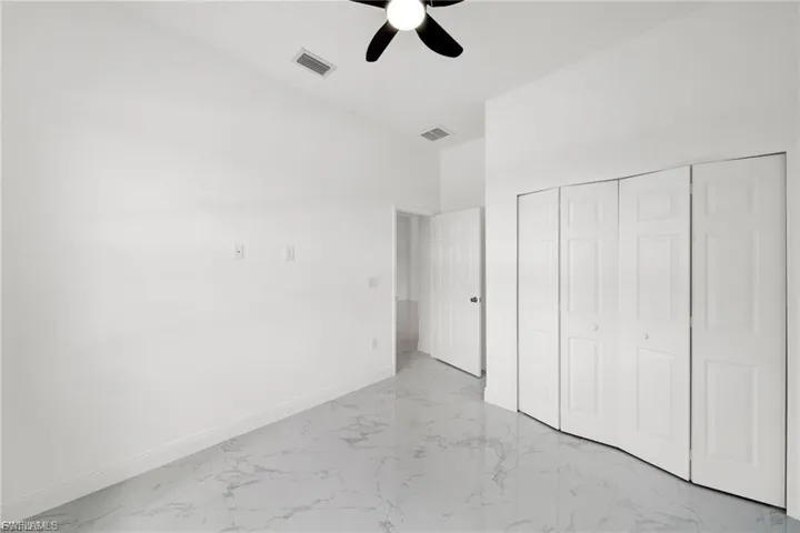 Unfurnished bedroom with light marble finish flooring, a closet, and a ceiling fan