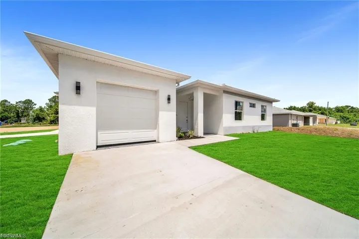 View of front of house with a front yard, stucco siding, concrete driveway, and a garage