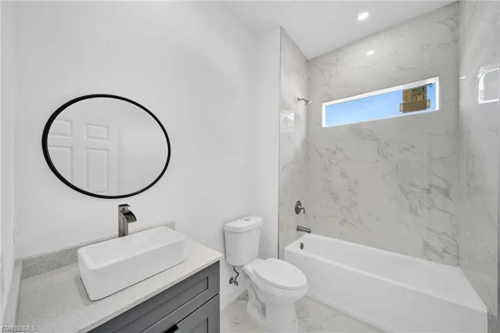 Bathroom with vanity, a combined bath / shower with marble appearance, and light marble finish floors