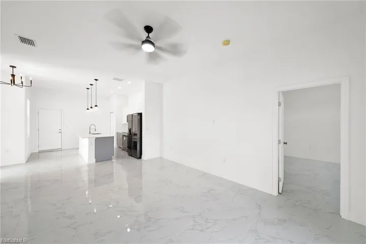 Unfurnished living room featuring light marble finish flooring and a ceiling fan