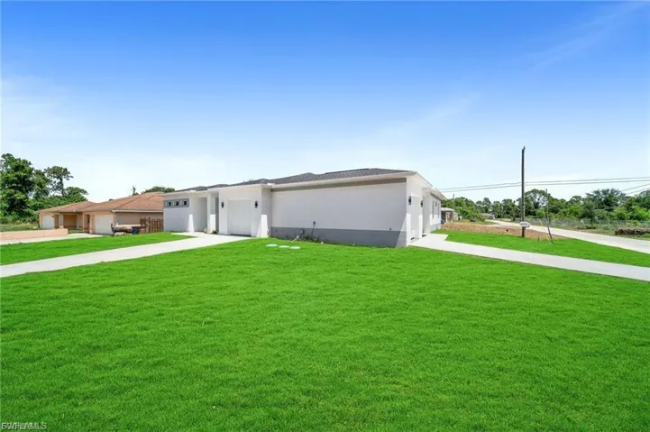 Prairie-style house with a front lawn, driveway, stucco siding, and an attached garage