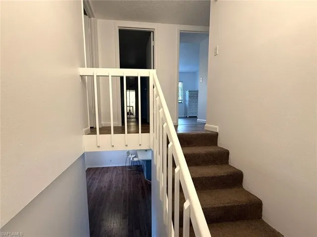 Stairway featuring a textured ceiling and wood finished floors