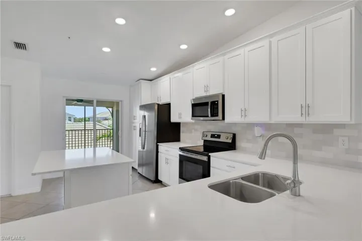 Kitchen with island and abundance of cabinets, slider to front screened patio space.