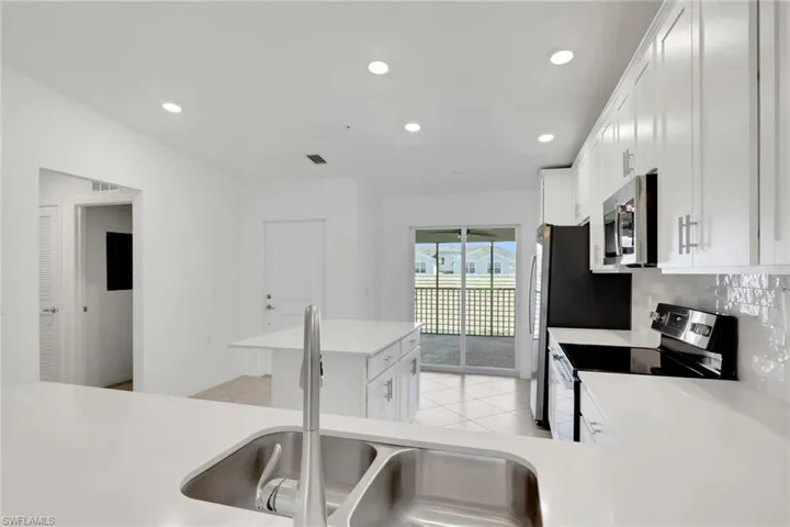 Kitchen with stainless steel appliances, tiled backsplash, quartz countertops