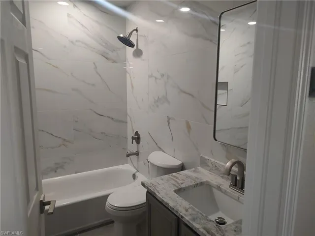 Bathroom with vanity, bathtub / shower combination, and tile walls