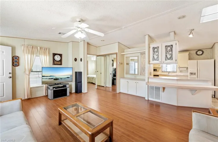 Living room with visible vents, a ceiling fan, a textured ceiling, and light wood finished floors