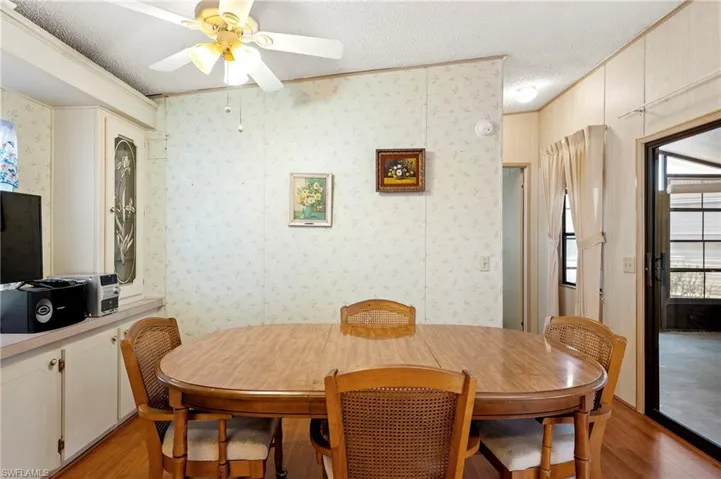 Dining room featuring ceiling fan, a textured ceiling, crown molding, wallpapered walls, and light wood-style flooring