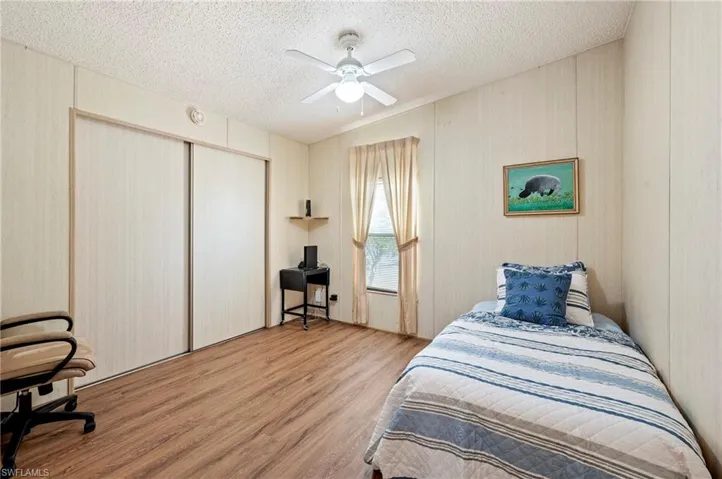 Bedroom featuring a textured ceiling, a ceiling fan, a closet, and wood finished floors