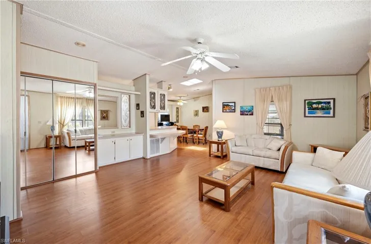Living room featuring a textured ceiling, ceiling fan, wood finished floors, and a healthy amount of sunlight