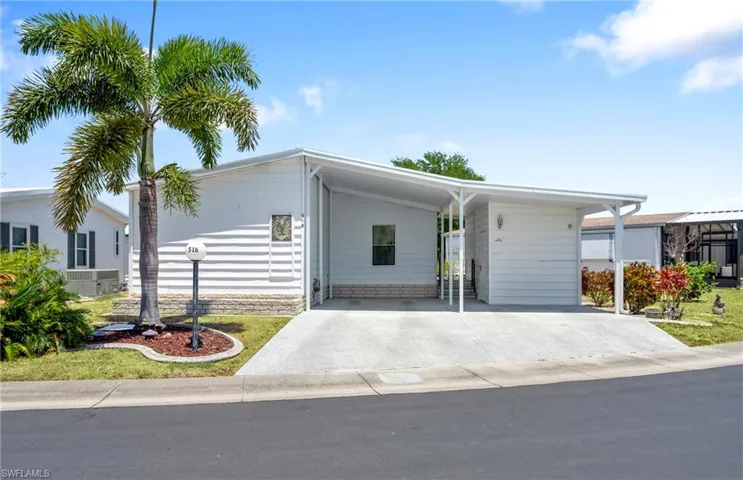 View of front of home featuring central air condition unit, an attached carport, and concrete driveway