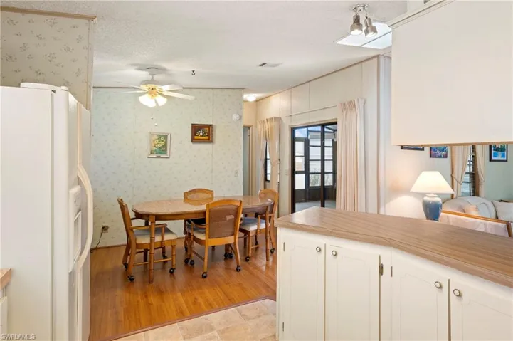 Dining room featuring light wood-style floors, a ceiling fan, a textured ceiling, and wallpapered walls