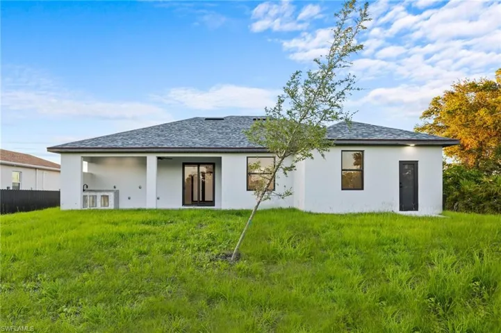 Back of house featuring a shingled roof and stucco siding