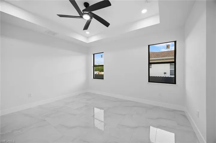 Spare room with baseboards, light marble finish floors, a raised ceiling, recessed lighting, and ceiling fan