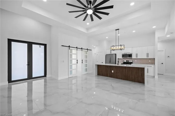 Kitchen featuring appliances with stainless steel finishes, a barn door, recessed lighting, french doors, and a high ceiling