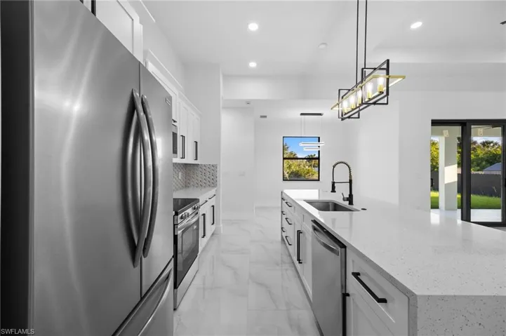 Kitchen featuring appliances with stainless steel finishes, a sink, recessed lighting, a large island with sink, and tasteful backsplash
